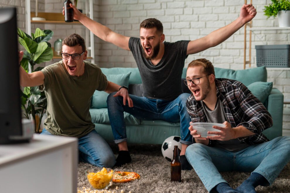 front view cheerful male friends watching sports tv together while having snacks beer